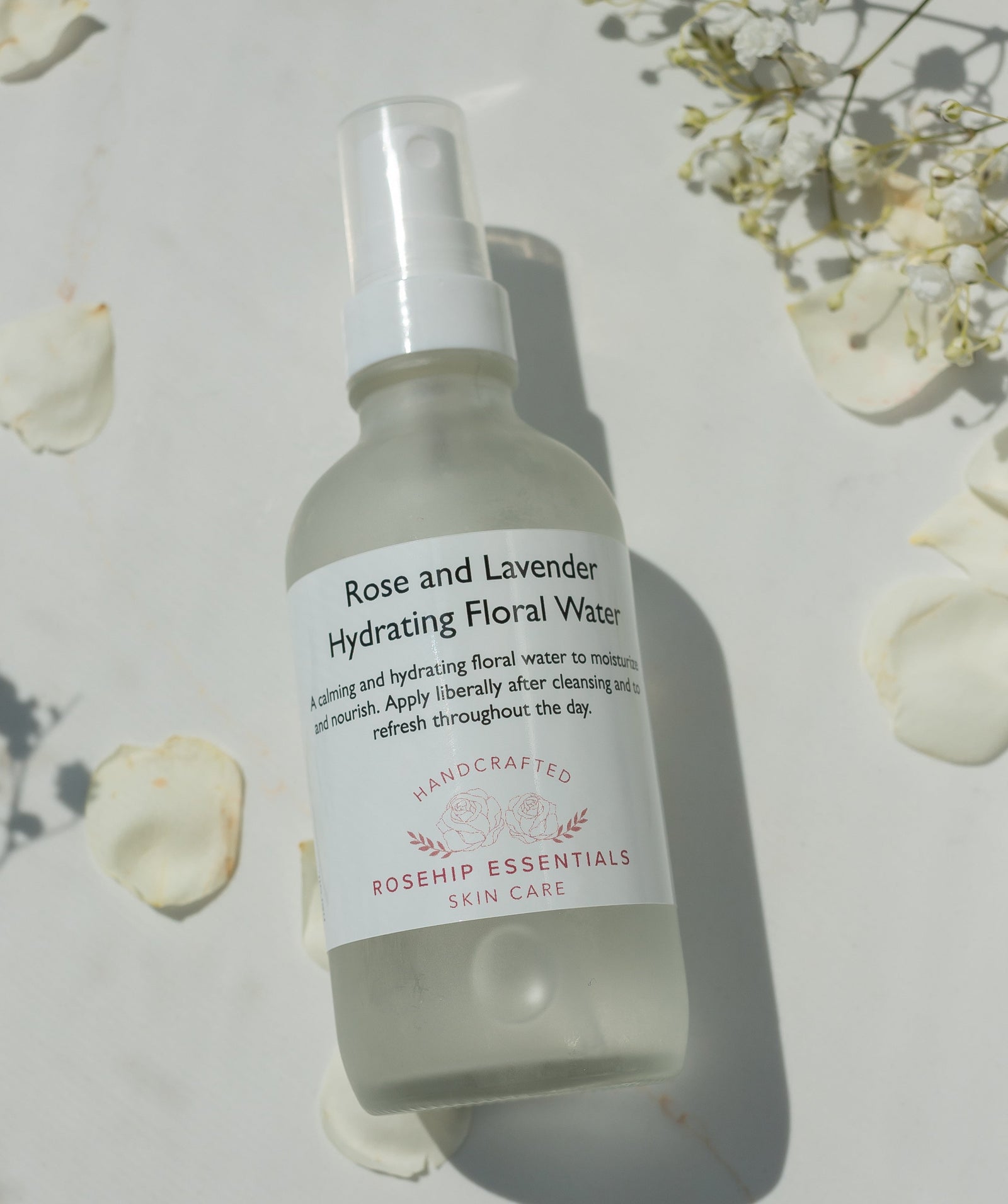 Bottle of Rose and Lavender Hydrating Floral Water from Roship Essentials on a light background with flowers.