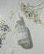 Bottle of Rose and Lavender Hydrating Floral Water with flowers and petals on a light background